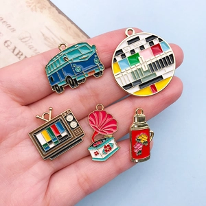 Macro detail of five retro enamel alloy charms including bus, TV, and phonograph on hand