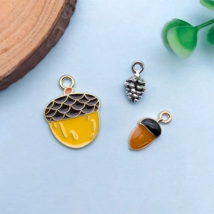 Detailed macro view of squirrel theme acorn and pine cone enamel charms for DIY jewelry making
