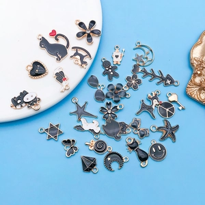 Surtido de dijes de esmalte negro para creación de joyas DIY en plato de cerámica blanca