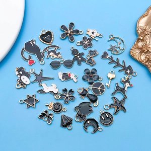 Vista plana de varios dijes de esmalte negro con detalles dorados para joyería DIY