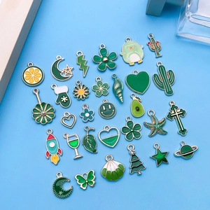 Vue détaillée de divers pendentifs en émail vert et blanc pour création de bijoux DIY