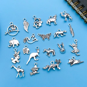 Variety of vintage silver animal alloy charms for DIY jewelry making on blue background