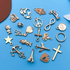 Close-up of golden alloy DIY charms including heart, plane and crown on blue background
