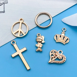 Macro view of gold-colored alloy charms featuring crowns, hearts, and crosses for DIY jewelry