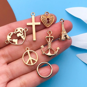 Macro shot of gold alloy DIY charms including Eiffel Tower and heart in hand