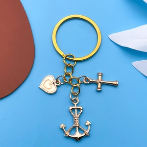 Detailed view of gold alloy charms featuring heart, cross, and anchor on a keyring