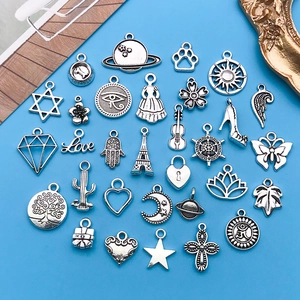 Flat lay of vintage Tibetan silver alloy charms in diverse shapes on blue backdrop