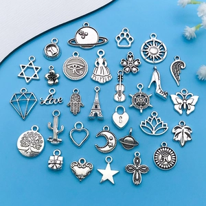 Collection of 30 vintage silver alloy charms for DIY necklaces and bracelets on blue background