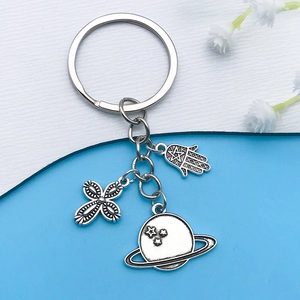 Detail of silver alloy keychain with Hamsa hand, cross star, and Saturn charms