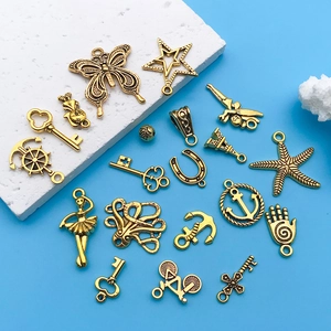 Macro shot of antique gold alloy charms featuring butterfly and anchor shapes for DIY jewelry