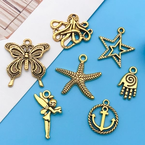 Detail of vintage gold alloy charms including butterfly, anchor and starfish shapes