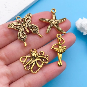 Macro detail of antique gold alloy charms featuring butterfly, starfish, and octopus patterns