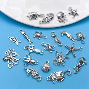 Flat lay of vintage silver ocean animal charms for DIY jewelry including seahorses and turtles