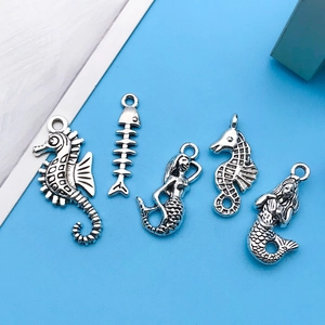 Detailed view of vintage silver ocean pendants including seahorses and mermaids for DIY