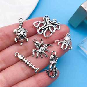 Detailed macro view of antique silver ocean themed charms held in hand for jewelry making