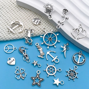 Macro view of assorted antique silver nautical charms featuring anchors and sea creatures