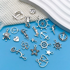 Macro shot of assorted antique silver nautical charms including anchors and mermaids