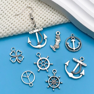 Macro detail of nautical silver alloy charms including anchors and mermaids for DIY jewelry