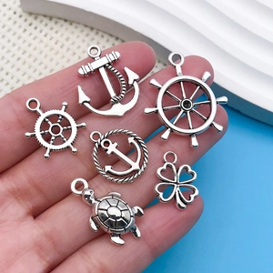 Macro shot of antique silver nautical charms including anchor and turtle on a hand palm