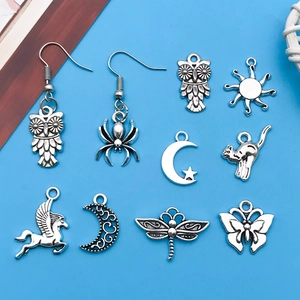 Detailed flat lay of antique silver alloy charms including owl, sun and butterfly shapes