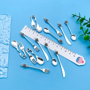 Macro shot of vintage silver cutlery pendants with crown details and sizing ruler