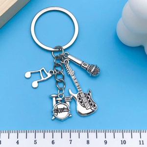 Polished silver music keychain with guitar, drum, mic and note charms on blue background