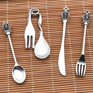 Macro detail of retro silver crown cutlery pendants including spoon knife and fork