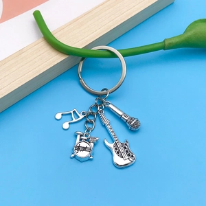 Detailed view of silver music-themed metal keychain with guitar, drum, and microphone charms