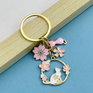 Close-up of pink cherry blossom and cat keychain with gold metal and pearl details