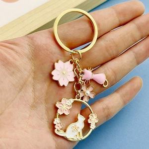 Detail of pink enamel cherry blossom and cat keychain with golden metal finish