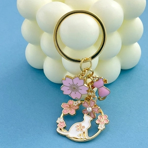 Close-up of golden keychain with pink enamel cherry blossoms and cute cat charms