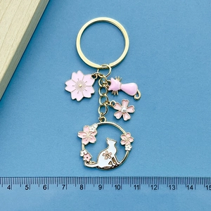 Detail of cute cat and pink cherry blossom keychain with measuring ruler for scale