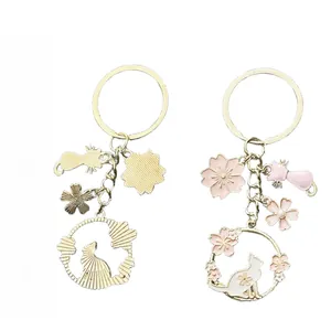 Front and back detail of pink cherry blossom and cat keychain with golden metal finish