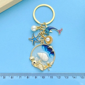 Detail of nautical keychain with starfish, blue dolphin, and shell-filled resin pendant