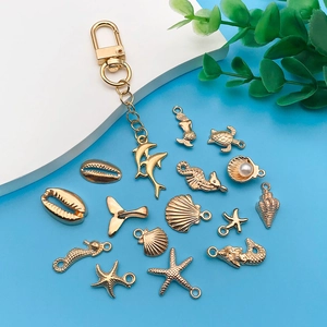 Detailed view of gold ocean charms including seahorse, starfish and pearl shell on blue backdrop
