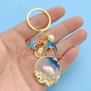 Detail of nautical keychain featuring blue starfish, dolphin, and seashell pendants
