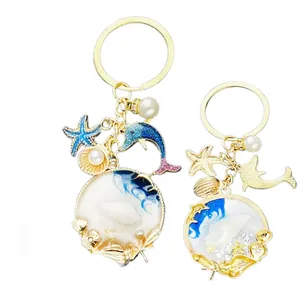Front and back view of ocean themed keychain with blue dolphin, starfish and pearl charms