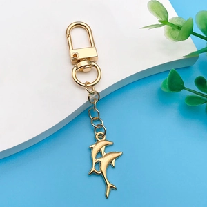Detail of golden dolphin charms on a keychain with a lobster clasp and blue background