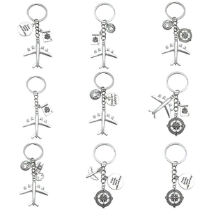 Various silver travel keychains with airplane, passport and compass charms in a grid