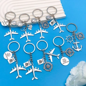 Travel-themed metal keychain with airplane, globe, compass and anchor charms on blue background