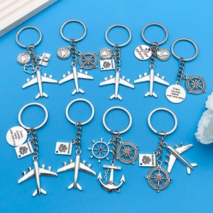 Silver travel keychain set with airplane, passport and globe charms on blue background