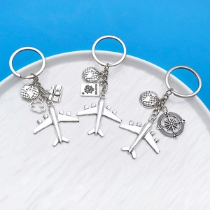 Detail of travel themed keychains featuring silver airplane, compass and passport charms