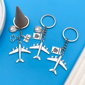 Detailed travel keychain set featuring airplane, passport and camera charms on blue backdrop