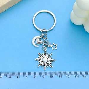 Silver celestial keychain with sun moon star charms on a light blue background