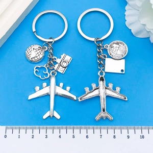 Macro view of silver airplane and globe charms on metal keychain over blue background
