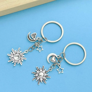 Vintage silver sun moon and star keychain set with heart detail on a blue background