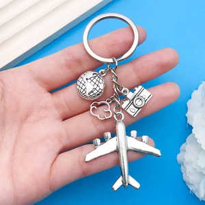 Close-up of travel keychain with silver airplane, globe, cloud and camera charms