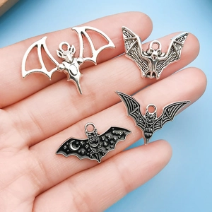 Detailed view of silver bat charms held in hand for Halloween jewelry making