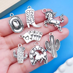 Detail showing vintage silver cowboy charms held in hand for jewelry DIY projects