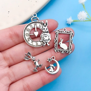 Macro shot of four vintage silver rabbit charms including a pocket watch and moon design
